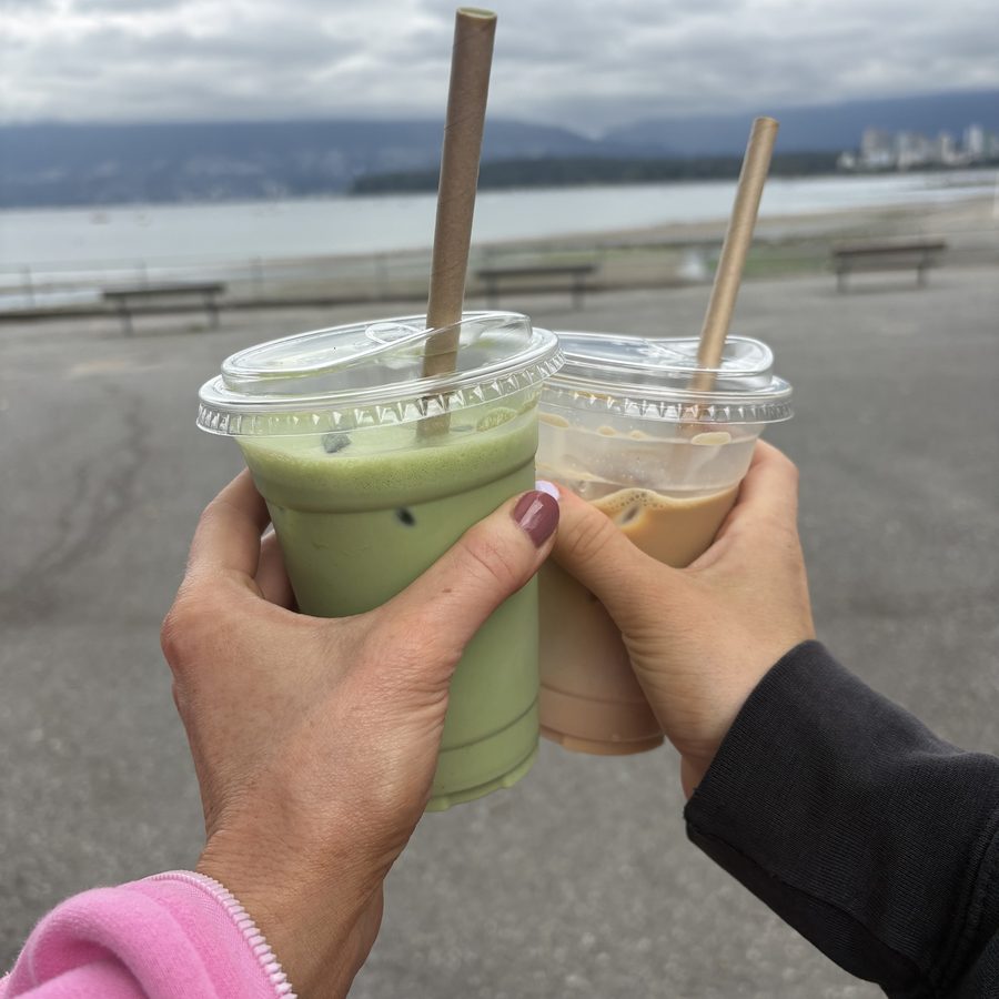Two takeaway drinks held beside a waterfront