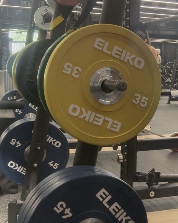 Yellow and black weight plates stored beside a gym rack